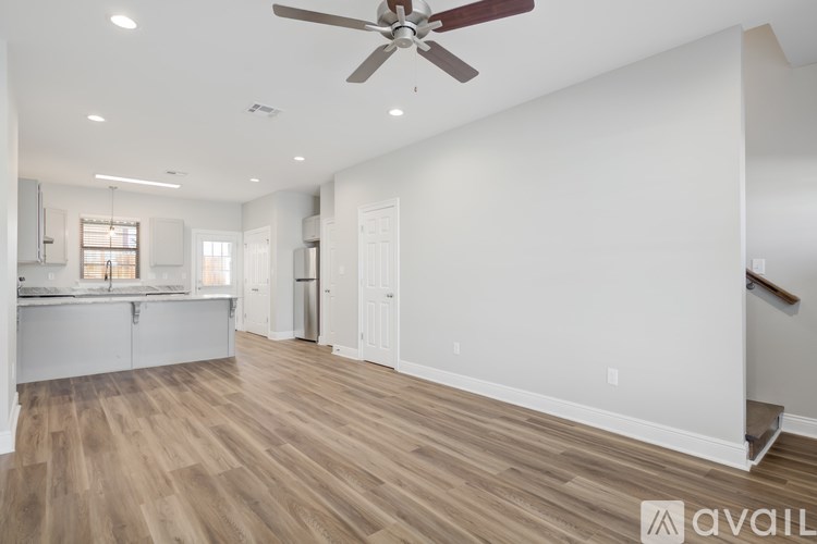 A spacious room with a ceiling fan and wooden flooring.