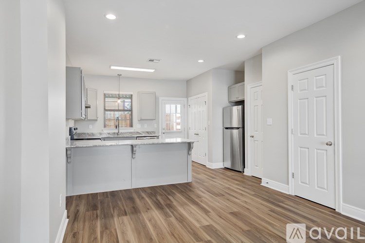 A modern kitchen with wooden floors and white cabinetry.
