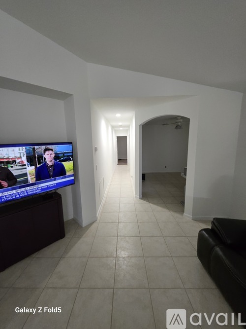A living room with a flat screen TV on the left and a couch on the right.