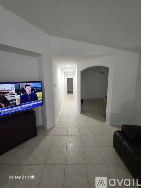 A living room with a flat screen TV on the left and a couch on the right.