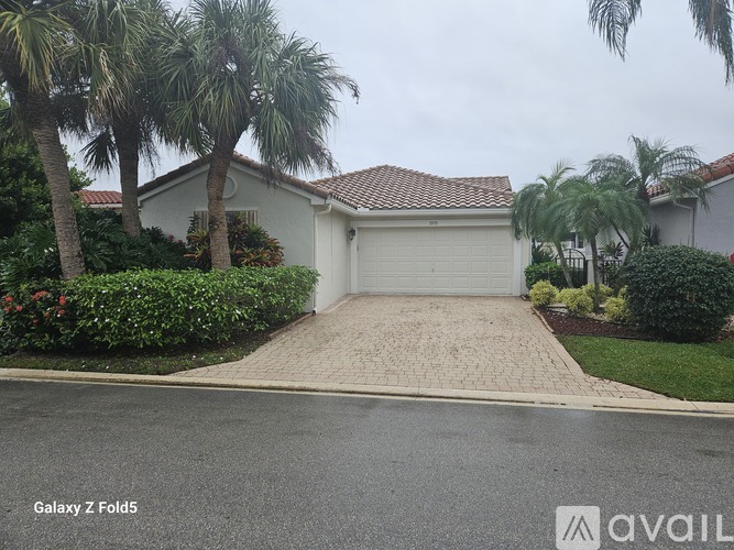 A house with a driveway and palm trees in front.