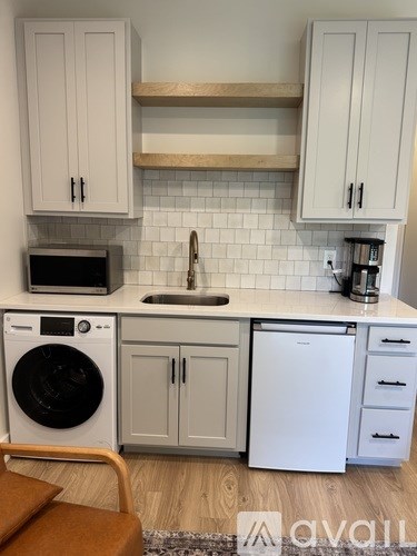 A kitchen with a washing machine and a microwave.