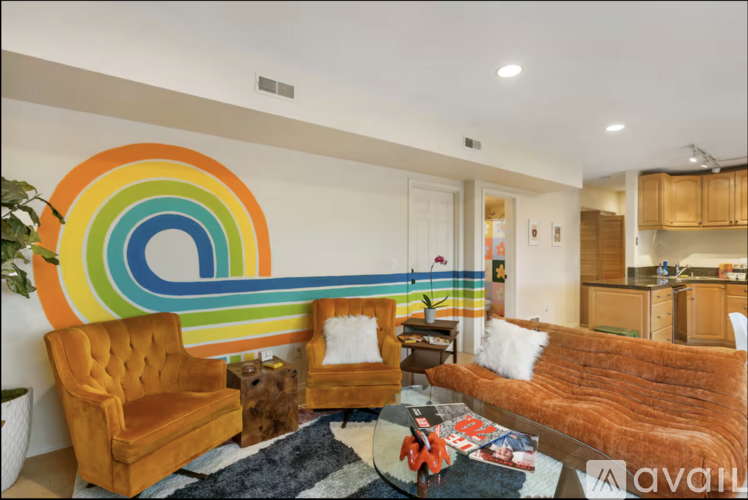A living room with a rainbow-colored wall mural and a brown couch.