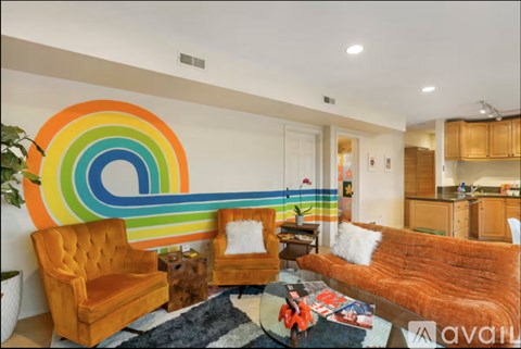 A living room with a rainbow-colored wall mural and a brown couch.