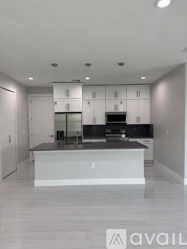 A modern kitchen with white cabinets and a black countertop.