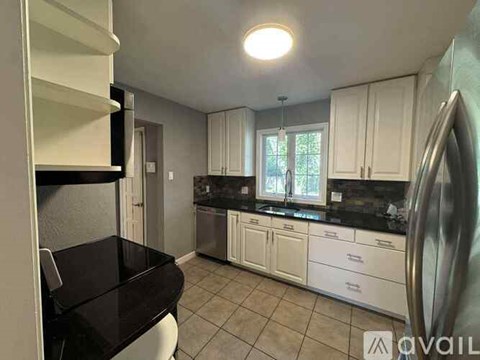 A kitchen with white cabinets and black countertops.