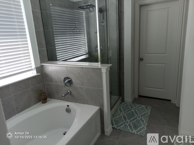 A bathroom with a white tub and a shower with a glass door.