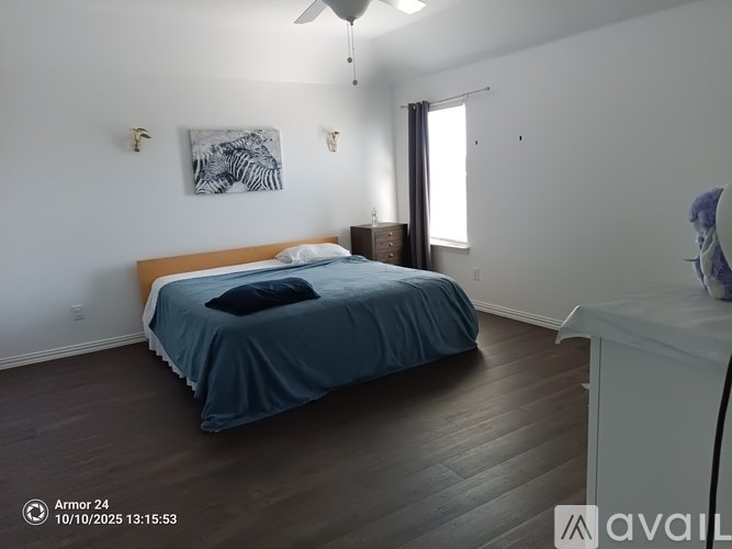 A bedroom with a bed, dresser, and artwork on the wall.