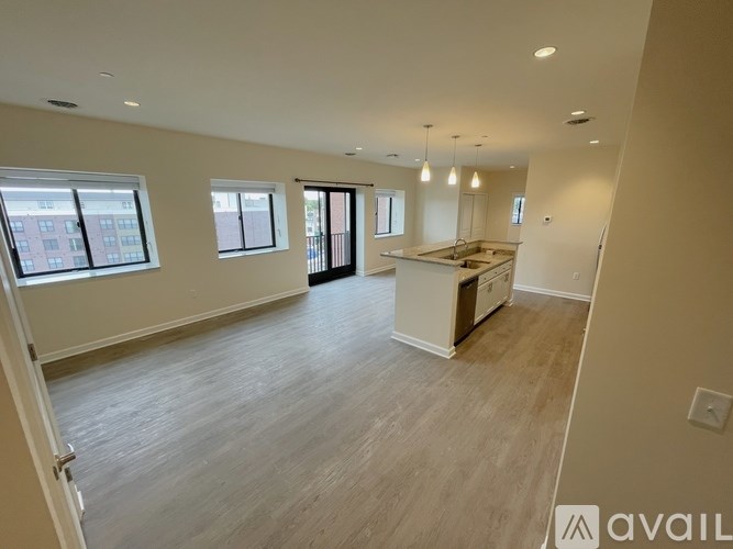 A spacious living room with a kitchen area in the background.