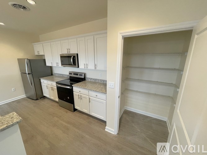 A kitchen with white cabinets and a refrigerator.