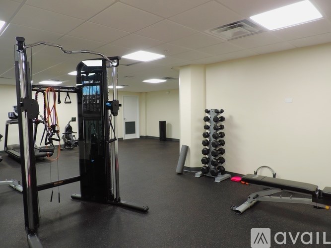 A gym with a variety of equipment including a squat rack, a leg press machine, and a cable machine.