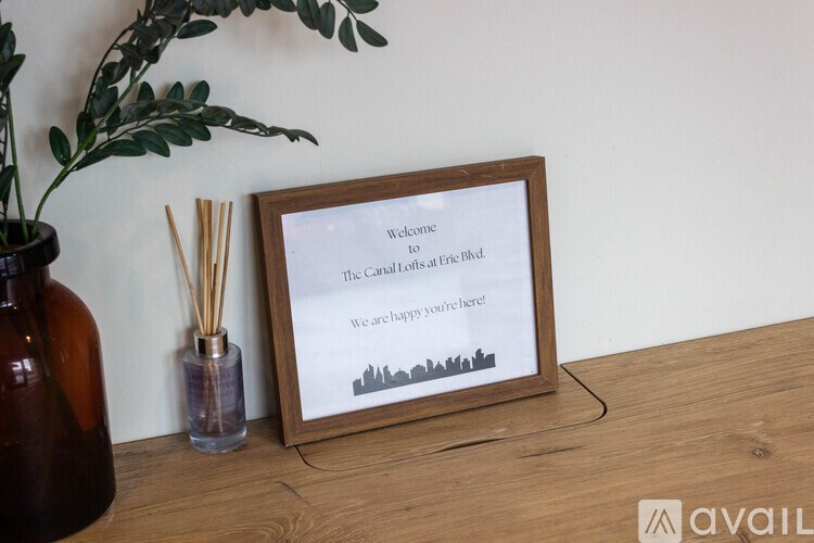 A welcome sign for The Cawley Offices at Erie Blvd sits on a table next to a vase and reed diffuser.