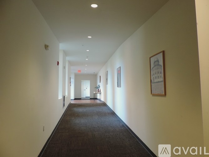 A hallway with a carpeted floor and white walls.