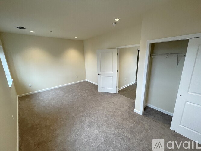 A spacious room with a carpeted floor and white walls.
