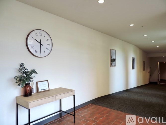 A wall with a clock and a table with a vase on it.