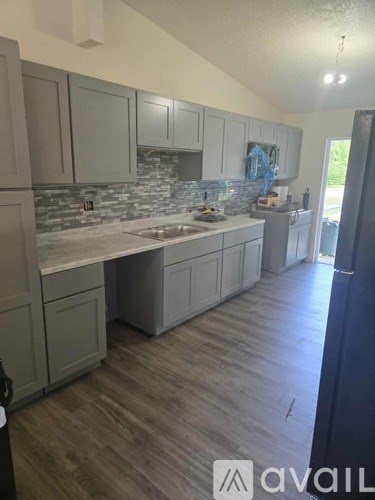 A kitchen with a stone backsplash and wooden floors.