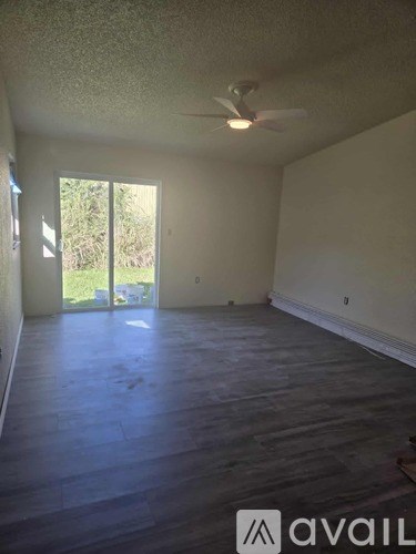 A room with a fan and sliding glass doors leading outside.