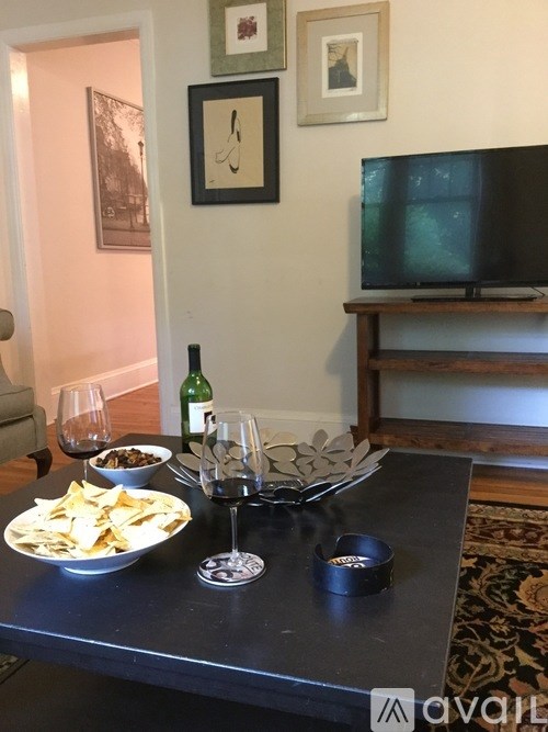 A black table with a bowl of chips, a glass of wine, and a bottle of wine on it.