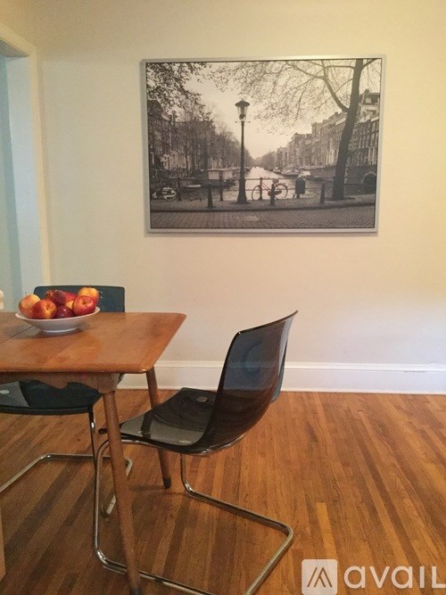 A black chair is in front of a table with a bowl of apples on it.