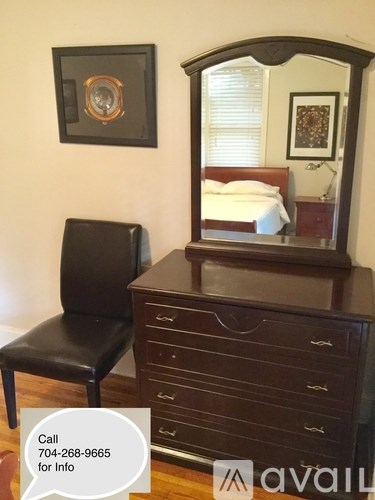 A black leather chair sits in front of a wooden dresser with a mirror on top.
