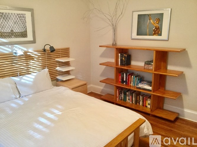 A bedroom with a bed, bookshelf, and a painting on the wall.