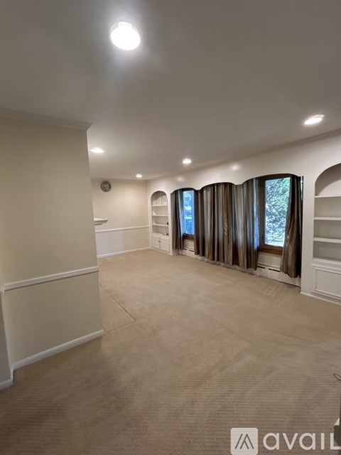 A spacious room with a large window and curtains.