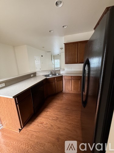 A kitchen with wooden cabinets and a black refrigerator.