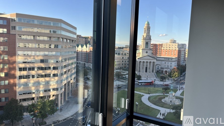 A view from a window looking out at a cityscape with buildings and a fountain.