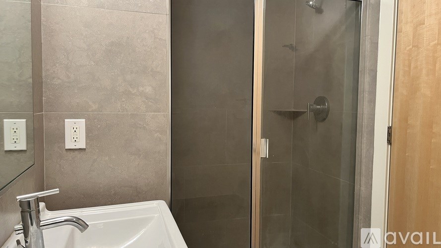 A bathroom with a white sink and a glass shower door.