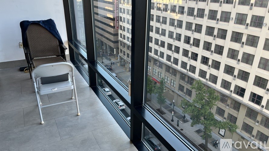 A chair is placed by the window with a view of a cityscape.