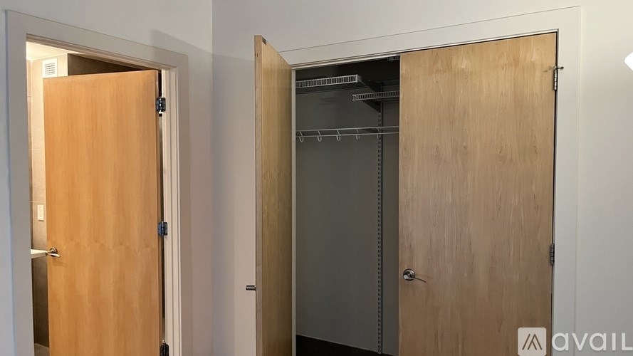 A wooden door is open to reveal a pantry with shelves and a white wall.
