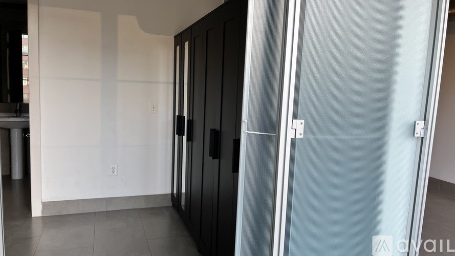 A room with a white wall and a black door.