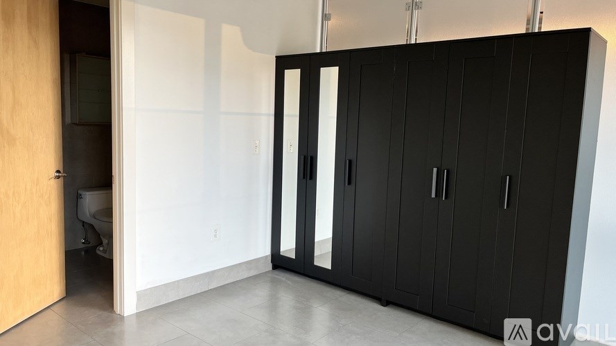 A black wardrobe with a glass door is in a room with a wooden door.