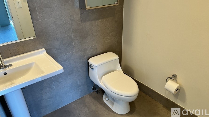 A white toilet is in a bathroom with a sink and mirror.