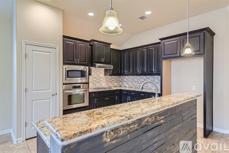 A kitchen with a granite countertop and dark cabinets.