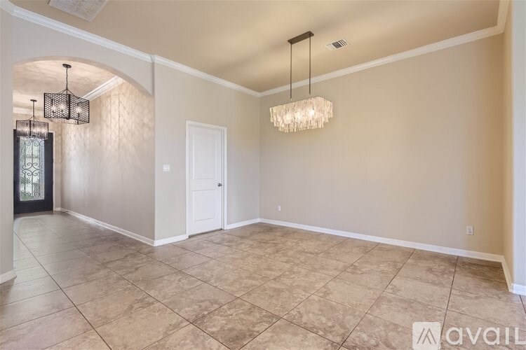 A spacious room with a tiled floor and a chandelier hanging from the ceiling.