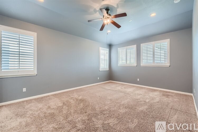 A room with a ceiling fan and carpeted floor.