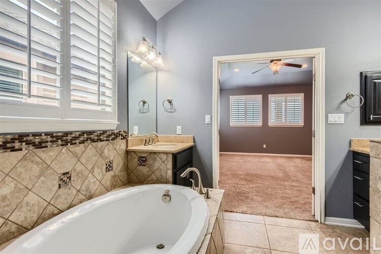 A bathroom with a tub, sink, and a mirror.