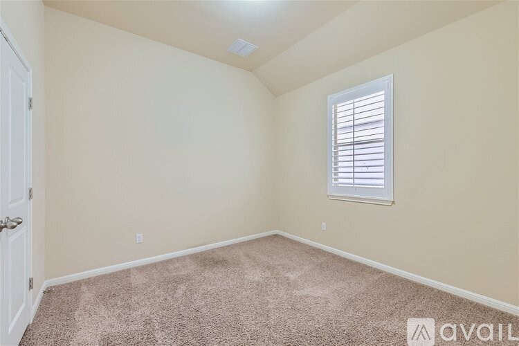A room with a carpeted floor, a window with blinds, and a door.