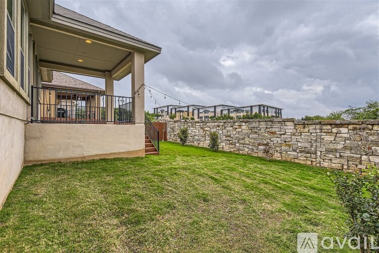 A house with a stone wall and a green lawn.