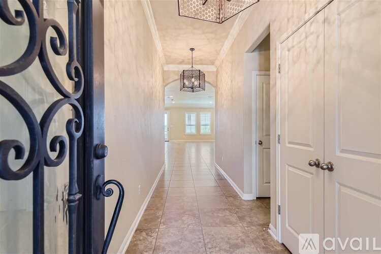 A hallway with a black gate on the left and a chandelier hanging from the ceiling.