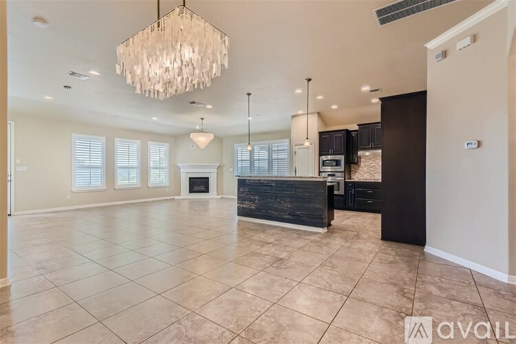 A spacious living room with a fireplace and a chandelier.