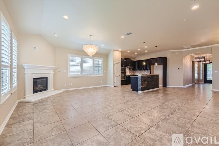 A spacious living room with a fireplace and a chandelier.