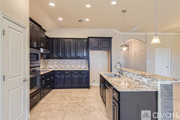 A kitchen with black cabinets and a marble countertop.