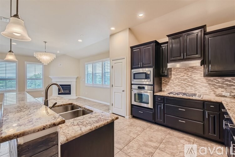 A kitchen with a marble countertop and dark brown cabinets.