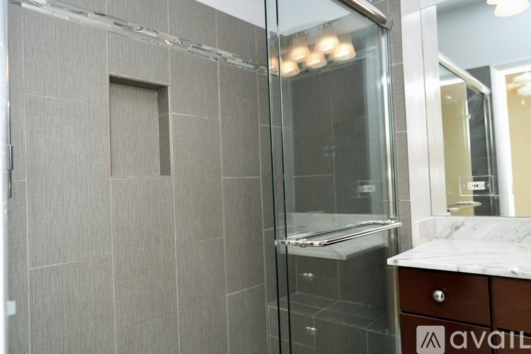 A bathroom with a glass shower door and a marble countertop.