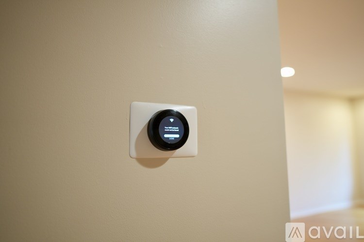 A wall-mounted device with a digital display is mounted on a beige wall.
