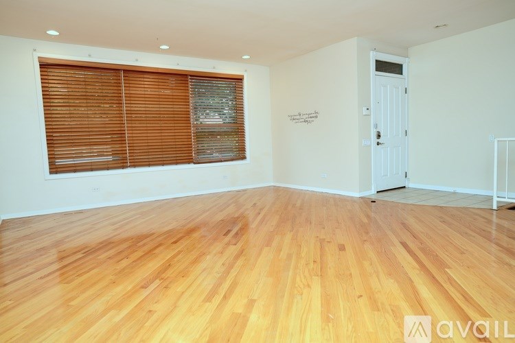 A room with wooden flooring and a window with blinds.