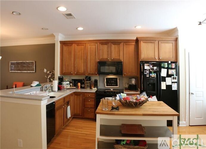 A kitchen with wooden cabinets and a black fridge.