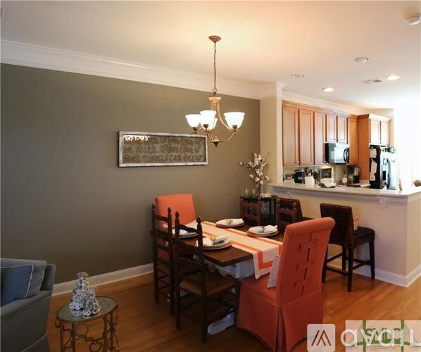 A dining room with a table set for four and a chandelier hanging from the ceiling.